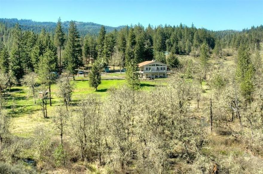 Enjoy basking in natures beauty from this magical hideaway nestled on over 18 scenic acres with seasonal ponds/creeks, and a fantastic year-round spring fed swimming hole. Bordered by BLM, you'll love the privacy, farming and 4H possibilities that the small barn and land offers. The main floor features an updated formal dining room, spacious open concept kitchen/living area w/expansive windows and French doors that lead to the 3-sided wrap around deck with handicap accessibility. Cozy up next to your choice of two wood burning fireplaces in either the living room or in the over-sized master bedroom that boasts an en-suite, large walk in closet, and tongue and grove vaulted ceiling. Downstairs features an additional living space, two bedrooms, full bathroom, laundry area and exterior access. The attached finished shop with two 10ft doors is perfect for any mechanic or hobbyist. With endless recreation opportunities, this premier property is a must see!