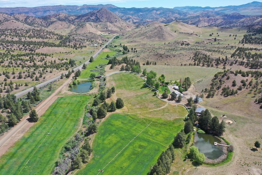 Don't miss this rare opportunity in Mitchell! Nestled on 217.52 acres across 3 parcels, this beautiful, well-maintained home features 25 irrigated acres with 2 wheel lines, hand lines, 2 ponds both stocked with bass and crappie, and 2 developed springs with Bridge Creek running through it. Enjoy stunning views from every window and the expansive wrap-around deck with a nice covered eating area with roll down screens, ceiling fan and tv and beautifully manicured landscaping, a tree lined driveway and garden area. Recent upgrades include a entirely new HVAC system and wired for generator back-up for peace of mind. Property includes a detached 2-car garage with storage/workshop, a massive 50x60 shop with plenty of room for all your projects and RV, equipment shed, hay barn, and loafing sheds, chicken coop, 2 diesel tanks and 1 gas tank and small greenhouse. A charming covered bridge over Bridge Creek adds to the property's unique charm. Schedule your private tour today!