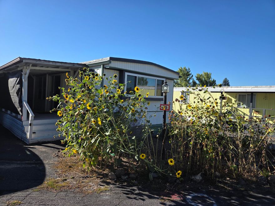 Welcome to this inviting manufactured home in a desirable 55+ community with live-in security guard and private road access for added peace of mind. Thoughtfully updated with newer doors, windows, and a handy doggy door, this home blends comfort with convenience. A versatile bonus room off the 3-car tandem covered carport provides extra space for hobbies, storage, or guests. Outside, the fully fenced yard with two gates and attractive landscaping offers the perfect retreat for pets and outdoor enjoyment. Ideally located near Crest Park, the OC&E Trail, and Mazama, you'll appreciate easy access to recreation and daily amenities.