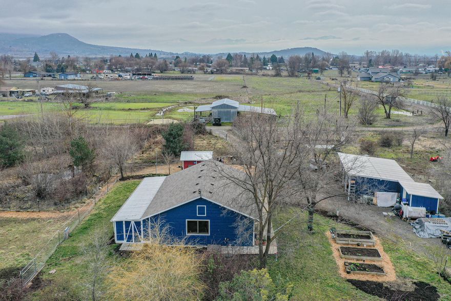 Darling cottage home on 1.26 irrigated acres with year-round pond.  Efficient use of space and storage in this open floor plan.  Attractive laminate flooring throughout.  Kitchen offers island with eating bar, smooth cooktop range/oven, refrigerator, dishwasher and pantry storage.  Built-in shelves and window seat.  Stack washer/dryer hook-ups in bathroom.  Enclosed sun porch.  Large chicken coop painted the perfect barn red.  Detached carport with 3 parking bays.  Incredible pond with trails and bridge to island and ready for the next campfire – it is like your own private nature park!  Rogue River Valley Irrigation District.  Public sewer.  2011 well log reflects 45 GPM for a 1-hour bailer test.  A perfect country retreat with views of the Table Rocks and Mt. McLoughlin.