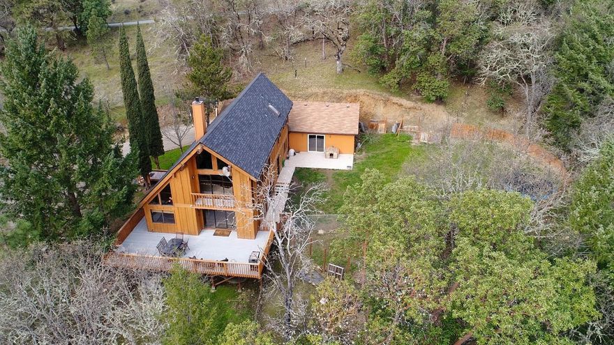 Private setting & end-of-the-road location on 1.92 wooded acres just a short distance to historic downtown Jacksonville & Britt Festival! Gated entry to spacious lodge-style home w/large picture windows, separate living & family rooms plus bonus loft. Vaulted, wood paneled ceilings add warmth & character. Beautifully updated kitchen (2017) offers granite counters, eating bar, stainless steel appliances: refrigerator, smooth cook top range/oven, microwave hood & dishwasher. Separated guest wing has 2 bedrooms - 5 bedrooms total throughout. Master suite has high vaulted ceiling & double closets. Indoor sauna. Linen storage & double sink vanity in guest bathroom. Basement offers extra storage. Finished two car garage plus carport. Room for RV parking. Fenced & cross-fenced. Updates include remodeled master bathroom 2018, HVAC & venting 2017, water softener & filter 2016, well pump 2016, flooring 2016, certified woodstove 2015, remodeled guest bathrooms 2016-2017 & newer roof.