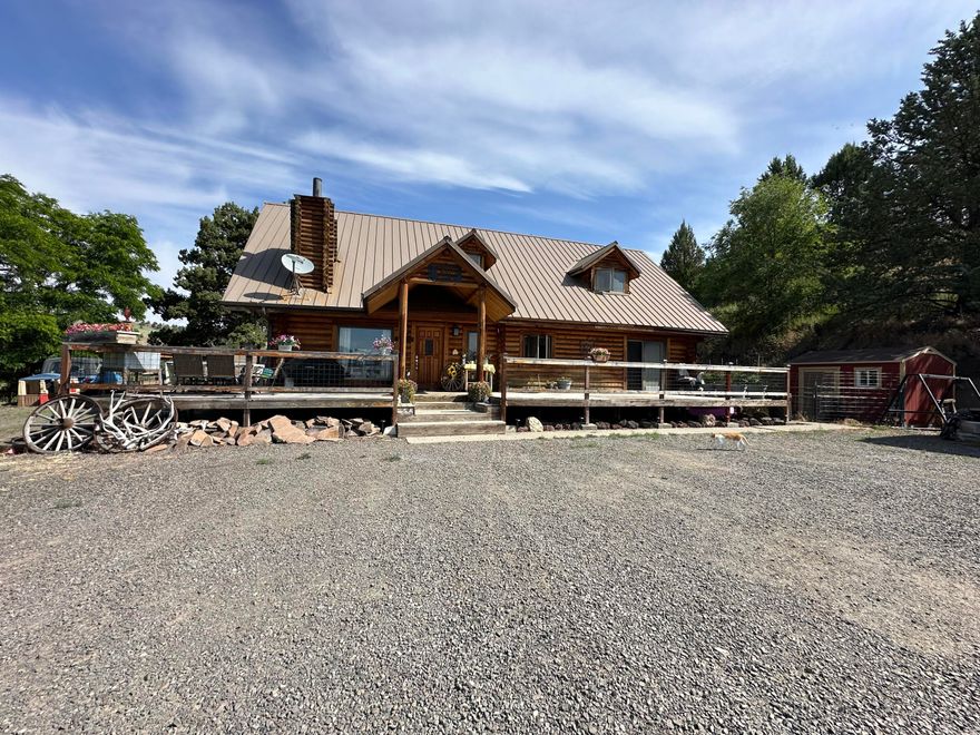 This two-story log home is situated on 3.94 acres at the edge of town, offering a total of 2,568 square feet of living space. It features three bedrooms, two bathrooms, and a den/office. The expansive open living area is enhanced by beautiful vaulted ceilings, and the property includes a central vacuum system as well as kitchen appliances. The home is fenced on three sides. With its charming country ambiance, the property boasts stunning views of the Strawberry Mountains from the wraparound deck, making it an ideal setting for entertaining friends and family. Additional amenities include a three-car detached garage, a hickory shed, and ample parking space. Nice Blazeking woodstove and electric furnace heat the home. Home was built in 1981