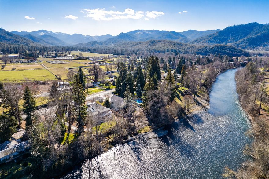 Stunning renovated country home with over 200 feet of Rogue River frontage between two lots totaling .84 acres! Inquire with agents for ample documentation of recent improvements including renovated main-level primary suite with black marble vanity and shower, kitchen with travertine stone tile floor, pull-out drawers, granite island with dining counter, stainless-steel appliances, new elevator, along with major upgrades to systems and utilities. Home features a spacious wrap-around porch, open-concept great room, high vaulted ceilings, abundant natural light from multiple skylights, gas fireplace with stone surround, library with built-in oak shelving, formal and informal dining areas, main-level guest bedroom and full bathroom; lower level includes a family room, full bathroom, and three additional bedrooms. Grounds with complete irrigation rights, beautiful mature trees, sunny gardening areas, split-cedar fencing, and steps for immediate access to the Rogue River!