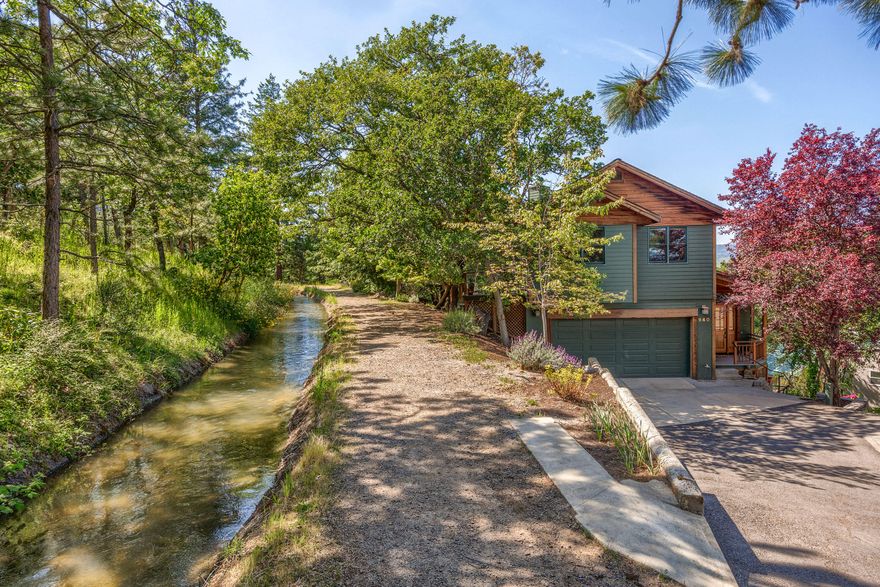 Nestled among beautiful Madrone and Pine trees, this custom home blends natural beauty with fine craftsmanship. Cedar ceilings, Pine & Hemlock window casings and Rift Oak cabinets showcase artisan woodwork. Designed for comfort and efficiency, it offers privacy and stunning valley views. Soak in the hot tub on the primary suite deck or relax on the brick patio under the trees. The primary bath features a slate shower and soaking tub. All bedrooms, second bath and laundry are upstairs, with the primary suite set apart. The main floor has slate flooring, vaulted ceilings, skylights and a gourmet kitchen with abundant cabinetry. Radiant heat warms both floors. All skylights operate automatically. The daylight basement is perfect for an office or rec room, full of natural light. Direct access from driveway onto a peaceful trail along seasonal TID flows. Enjoy Ashland's vast hiking and biking trails, with shopping & schools nearby offering the balance of relaxed and active living you seek.