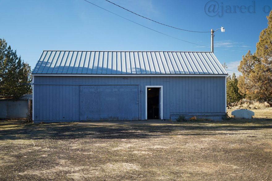 960 sqft shop located in the quiet Prineville Lake Acres community. Built in 1996, this fixer-upper property offers great potential for storage, hobbies, or workspace. The land is mostly level, making it an excellent opportunity to build or place a home. It includes an RV hookup, cistern well, 1,000 gallon capfill septic system, and power on site. The shop features a metal roof replaced just over five years ago. The property is fenced along the sides and back with a nice rock wall in front, adding character and privacy. Enjoy peaceful country living just a short drive from downtown Prineville, local amenities and a short drive to Prineville Reservoir. Low road association dues make this an affordable and flexible opportunity in Central Oregon.