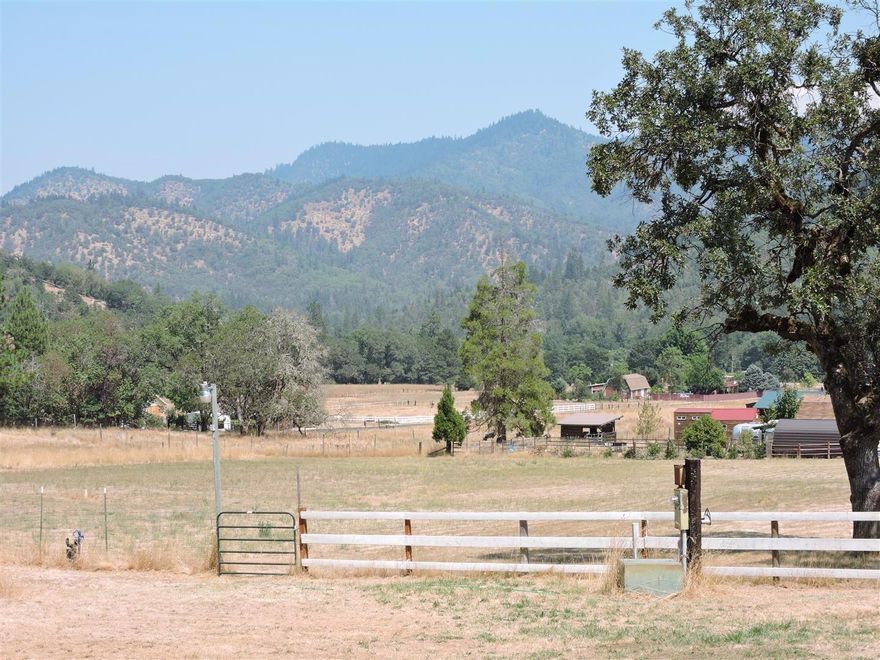 Picturesque Mini-Ranch Near Rogue River. Lovely 12+ acre peaceful setting with towering trees, level fenced pasture, big pole barn with shop area and small animal shelter too. Well-built 1,792 barn-style home has two woodstoves, new mini-split heating system, laminate wood flooring, updated windows and plenty of room for your artistic touches. Good well, 4 bedroom septic, good sprinkler setup, extra storage buildings could be updated. A wonderful opportunity!