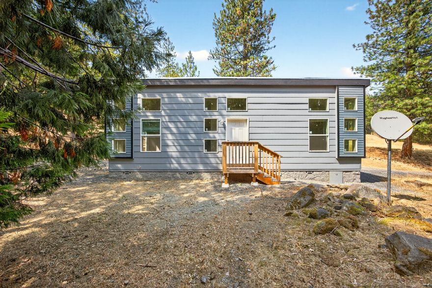 If you've been dreaming about a peaceful home surrounded by beautiful mountains yet still close to town, this could be the one! Practically brand new, this 2024 built home is perfectly placed in a sunny spot on nearly 5 acres. Located at the end of Wagon Trail Drive, you are only a handful of minutes away from Jacksonville shopping, Britt and restaurants, while enjoying your own wooded acreage and trails to explore. Well and septic are established, electricity is connected and everything is move-in ready! This modern tiny home features one bedroom with additional loft space, one full bathroom plus a designated indoor laundry area. The open concept Living Room and Kitchen area feature vaulted ceilings and many windows to take in views of the trees and wildlife. This property borders BLM and sits above the fog line during the Winter so you benefit from privacy and an ideal elevation on an easily accessible road. There is cell phone service and internet available!