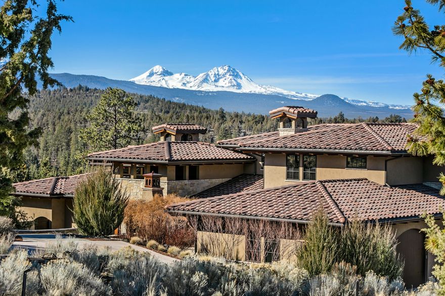 Majestic Cascade Mountain Views & the peaceful sound of the Deschutes River below complement the luxurious interiors of this spectacular residence. Wood & stone accents blend w/ the natural scenery surrounding the 1-acre property, ideally positioned in the exclusive North Rim community. Home embodies rustic elegance, w/ hand-hewn timbers, entry foyer accentuated by stone columns & 17' ceilings leading to 2-story great room w/ vast picture windows & deck overlooking panoramic mountain views. Main level primary suite offers private deck & hot-tub from which to enjoy the mountain views, sunsets & the rising sun.  Main level also inc. 2nd primary suite; library overlooking garden courtyard; mtn view chef's kitchen; dining room w/ fireplace; study w/ access to 2nd courtyard w/ fireplace. 2 guest suites, family room w/ kitchenette, mountain view terrace & 2nd laundry up.  Lower-level features rec room, workshop & gym w/ access to outdoors & river below. Home also boasts TWO separate garages
