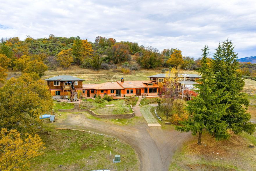 Welcome to your own oasis: a truly unique property offering 3 living spaces on nearly 5 peaceful acres w/ beautiful mtn & valley views 5 minutes from downtown Ashland. Whether you're seeking a multi-generational home, income-producing rentals, or a private retreat, this property provides incredible flexibility. The main home (built in 2011), blends creativity & comfort w/ American clay walls, radiant heat floors, & an open-concept layout filled w/ light. The spacious kitchen is ideal for entertaining, flowing seamlessly into a large living area w/ tranquil mtn views. It features a large primary suite on the main level, an additional bedroom/office, and a great room — perfect for family gatherings or guests. Connected yet distinct, the original home offers 3 bedrooms, 2.5 baths, & a large multipurpose room w/ a passive solar sunroom. A separate studio apt w/ a private entrance adds even more versatility. Outside, enjoy the rolling pasture, vineyard, garden space & breathtaking views.