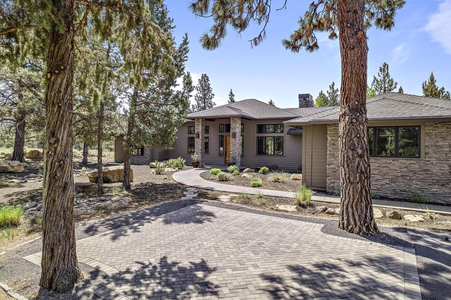 Nestled at the base of the Three Sisters, tucked between the pines lies the perfect fusion of northwest and contemporary architecture. Designed with nature in mind, this home effortlessly blends into the natural landscape. Large glass windows emphasize the sunny, southwestern exposure, while dramatic stone fireplaces highlight the living room and extended living beneath the covered patio. Clean lines, warm wood accents, and countless thoughtful design elements bring the outdoors, in. Enjoy meals in the sunlit breakfast nook, dining room, or beneath the stars with the outdoor fireplace to warm you.  The primary suite is on its own wing and features a steam shower and soaking tub. There are two spacious ensuite bedrooms plus a large office. A timeless and quality build by local craftsman, Mahler Homes. Owner willing to carry at exceptional terms for qualified buyers.