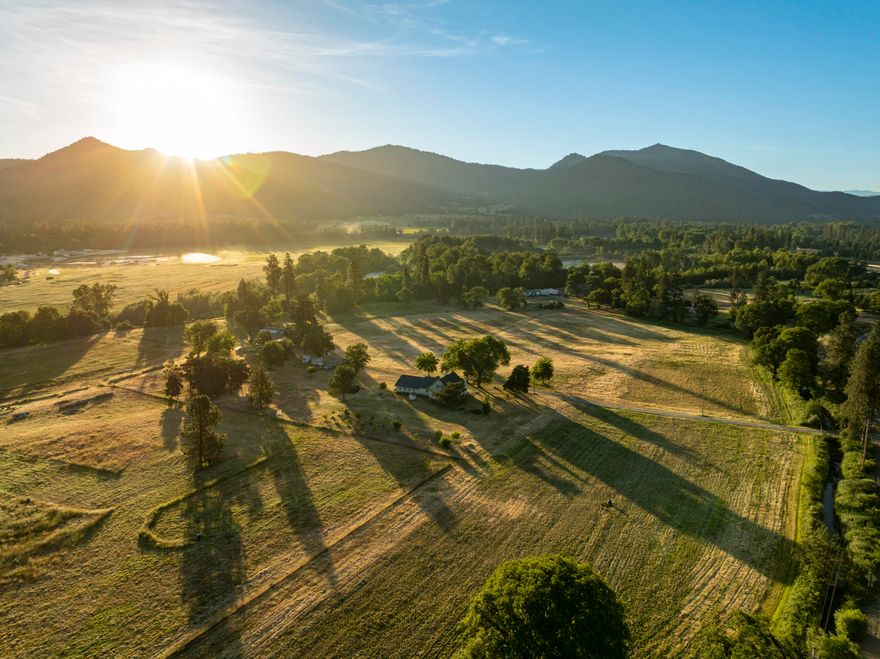 Applegate Riverfront ranch featuring 36.31 acres of irrigation rights from the Applegate River and over 1,100 feet of river frontage. The land is level, fenced, and productive, with a modern irrigation system. The ranch spans four tax lots and includes a 1,764 SF single-level home with a 960 SF attached garage, plus a 4,800 SF barn and 1,200 SF milk barn partially converted to future living space. A nearly finished shop offers high-quality space. A rare opportunity for irrigated acreage with live water, infrastructure, and flexibility in Southern Oregon's Applegate Valley.