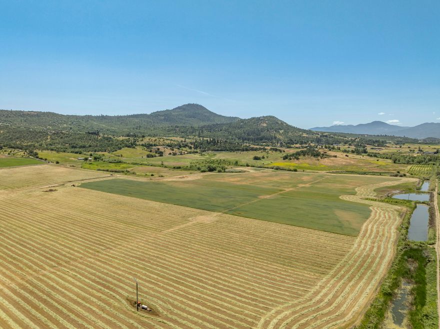 Welcome to the South Parcel of the Foothills Irrigated Farm—nearly 140 acres of productive ground with 133.5 acres of Medford Irrigation District water rights, ponds, and efficient layout for farming. A gently rising southern knoll offers panoramic views of the Table Rocks and surrounding valley, presenting a potential homesite location (buyer to do due diligence; not yet applied for). The mostly Class III soils support diverse agricultural uses, and infrastructure includes nearby city water, three-phase power, and gravity-fed mainlines. With excellent visibility at the corner of Foothill and Vilas Roads, the property also offers strong potential for a farm stand or other ag business. Conveniently located just minutes from Medford, I-5, and the Rogue Valley International Airport, this property blends rural beauty, utility, and access in one of Southern Oregon's most desirable agricultural regions.