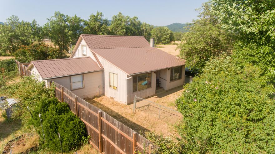 Charming Country Farmhouse on 1/2 acre-Low Maintenance Living! Enjoy the beauty of country living without the upkeep! This inviting two-story farmhouse sits on a manageable .50 acre parcel zoned EFU in the scenic pastured countryside of Holland Loop. With a gated driveway (plus 2nd entrance), fenced front yard, fruit trees, seasonal creek, and lush garden areas, the setting is private and picturesque. The home offers a spacious layout with 3 bedrooms and a versatile bonus area. The large kitchen includes an adjacent utility/laundry room, and an expansive living room is flanked by 2 additional rooms perfect for a formal dining space, home office, library, or sitting room. Two bedrooms are located downstairs, with the third and bonus space upstairs. The generous bathroom features a jetted soaking tub and separate shower. There is a carport attached to the home and an extra shop/storage area-perfect for projects or extra storage and new Daikin mini split system installed.