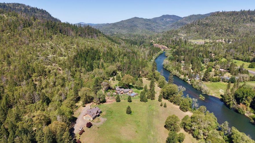 Nestled along nearly a ¼-mile of Rogue River frontage, this premier 73.98-acre estate offers a rare combination of luxury, privacy & natural beauty. The 3,547 sq. ft. home features 4-bdrms & 3-bath, with vaulted ceilings, hardwood & tile flooring, solar system & 2-stunning river rock fireplaces. The spacious kitchen boasts an island & pantry, while the formal dining room & family room provide ample gathering space. The main-floor primary suite includes a soaking tub for ultimate relaxation. Outdoor amenities abound, from the covered BBQ area & in-ground pool to the sauna and pool house. A custom 2,800 sq. ft. barn/shop with cement floor & loft, 30x30 2-car garage, irrigated 20-acre pasture + 54-acres of forest & abundant wildlife make this property ideal for equestrian or outdoor enthusiasts. Bordered by 1,000's of acres of public land, with excellent salmon fishing, seasonal creeks, and breathtaking mountain views, this gated retreat is just minutes from Lost Creek Lake.