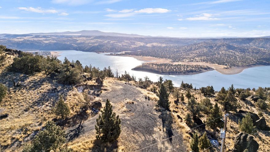 Exclusive gated community, 3.9AC parcel w/ breathtaking, panoramic views of the Prineville Reservoir and surrounding mountains. At the end of a quiet cul-de-sac, cleared w/ graveled Rd leading to both homesite and shop site! Underground power installed, w/ meter bases for both locations.  For added convenience, 50-amp RV hookups w/temp power available at both locations, making this site ready for immediate & convenience while you plan your dream home. Water lines installed underground from street meter to homesite and shop site, w/temporary hookups at each site. RV septic lines run from shop area to the approved septic zone, w/septic area approved for a standard system.This property is in a neighborhood of custom homes, offering exclusive & tranquil setting, just 15 mins south of town. W/ public boat ramps a short distance away, it provides perfect blend of peaceful living & outdoor recreation. This stunning parcel is a rare find, combining beauty, convenience & endless potential.