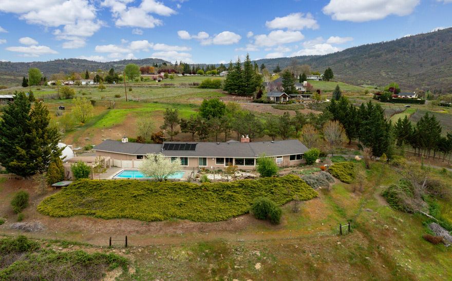 Extraordinary home on 10+ acres with breathtaking mountain and valley views. This home is all on one level and features 4-bedrooms 3-bathrooms, 1-half bathroom, granite countertops, tile floors, vaulted tongue and groove wood ceilings, massive brick fireplace, kitchen with stainless steel appliances, breakfast bar, wine storage, walk-in pantry and more! Outside features a huge solar heated in-ground pool with electric cover, amazing garden/orchard, 7.3-acres of Talent irrigation, 24x38-shop, oversized 3-car garage, large drive-through carport. Too many amenities to list!