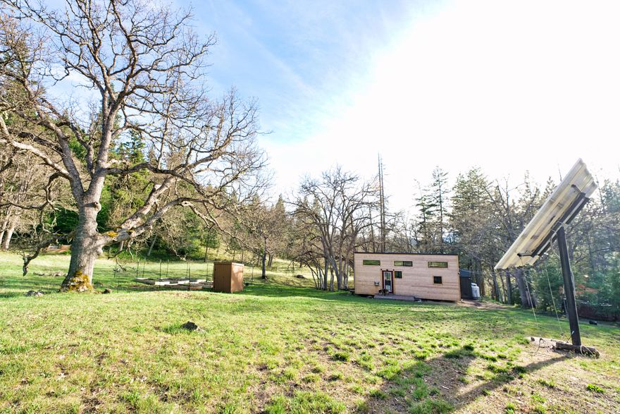 Come cool off at this mountain oasis! This gorgeous 5.44 acre parcel has 9 structures on it with a professionally built tiny home, 3 detached bedrooms, a central communal kitchen/bathroom, and several utility buildings. This property is served by a 1.6 KWH solar system array, however, power is available at the driveway if desired.  A sand filter septic system was installed in 2015 and the well produces a consistent 7gpm - also served buy a 1500 gallon gravity fed holding tank. This property would be a perfect group recreational property, a vacation rental (sleeps 10), or great for building your dream home! Many possibilities exist. Buyers to perform all due diligence related to property, uses, and structures. Sale includes washer/dryer, backup generator, wood-fired hot tub, solar equipment, and sheds. Contact Listing Agent for possible financing options. Owner may be willing to finance with large down. Buyer to perform their due diligence for desired use of the property.