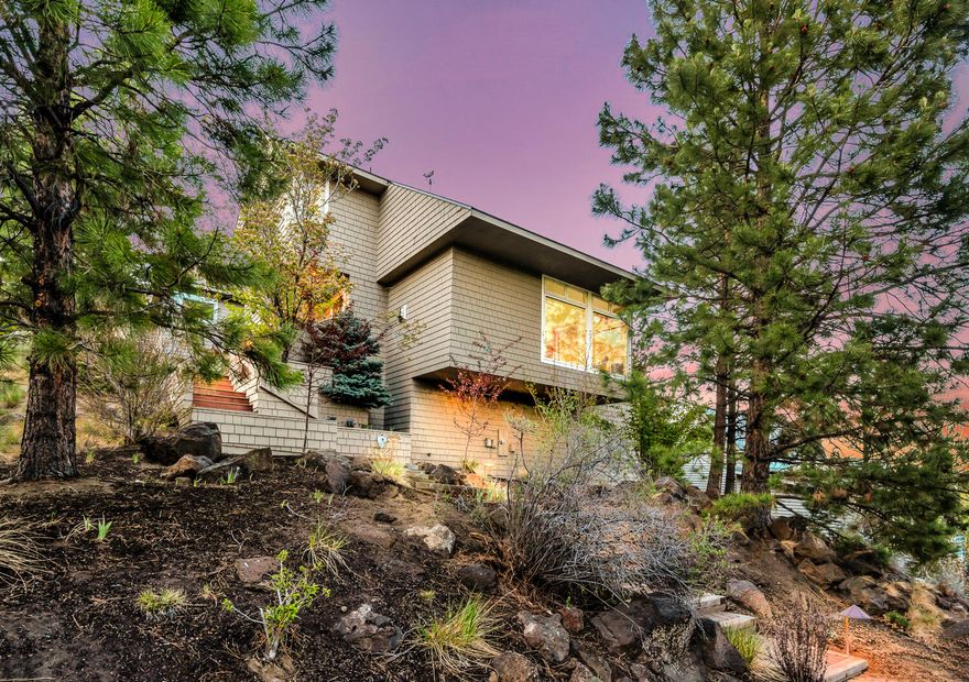 Tucked on a quiet cul-de sac just above First Street Rapids, this lovely home was designed around the natural contours of lower Awbrey Butte and custom built in 1992.  First time on the market, the split level floor plan has a generous kitchen and entertaining space connecting the main living area and deck. Large floor to ceiling windows look towards Pilot Butte and the tree tops. Abundant natural light with thoughtfully designed window placement and skylights throughout.  Open any of the awning windows and hear the Deschutes as it rushes through First Street Rapids. The primary suite faces the river with a second junior suite on the same level. There is a third bedroom and vaulted bonus room that could also be utilized as a craft/art or media room.  Both rooms are just off the main level living space.  Private alley access with a flat entry to the two+ car garage. 16 Solar panels power the home. Trailer parking pad, new roof and skylights (2021), & HVAC system (2018).
