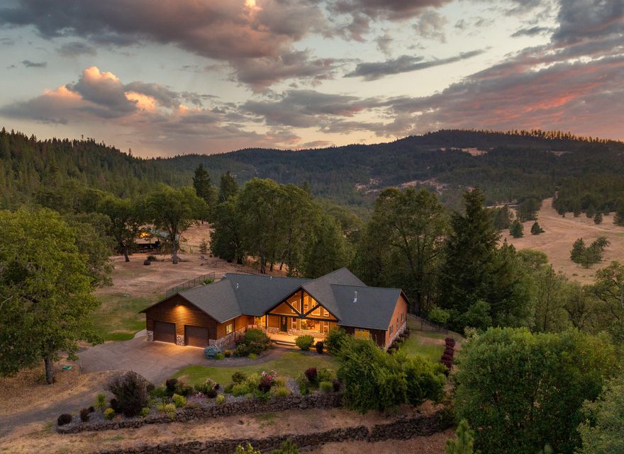 Welcome to Acosta Family Ranch & Estate, a serene 79-acre property with rolling terrain, pastures, mature oaks, & wooded areas. The 4-acre private knoll features a deer-fenced homesite including the estate home, shop w/guest quarters, barn, chicken coop, & garden space. The home showcases Northwestern charm with rustic wood beams, real log siding, & lush landscaping, while also boasting grand vaulted ceilings, an open floor plan, kitchen, 3 bedrooms, & 2 bathrooms. The backyard offers an inground pool w/an impressive rock water feature & hot tub. The guest quarters provide 1,400+ SF w/kitchenette, 3 bedrooms, & 2 bathrooms. The attached shop spans 1,200 SF plus a 50-ft long carport. The 3,300 SF barn is great for animals or equipment, 1,800-ft grass runway with hangar, & wood shed round out this feature rich property. The area has abundant wildlife like deer, elk, & bear, & offers hunting opportunities. Located near Shady Cove, this peaceful retreat is perfect for outdoor enthusiasts.