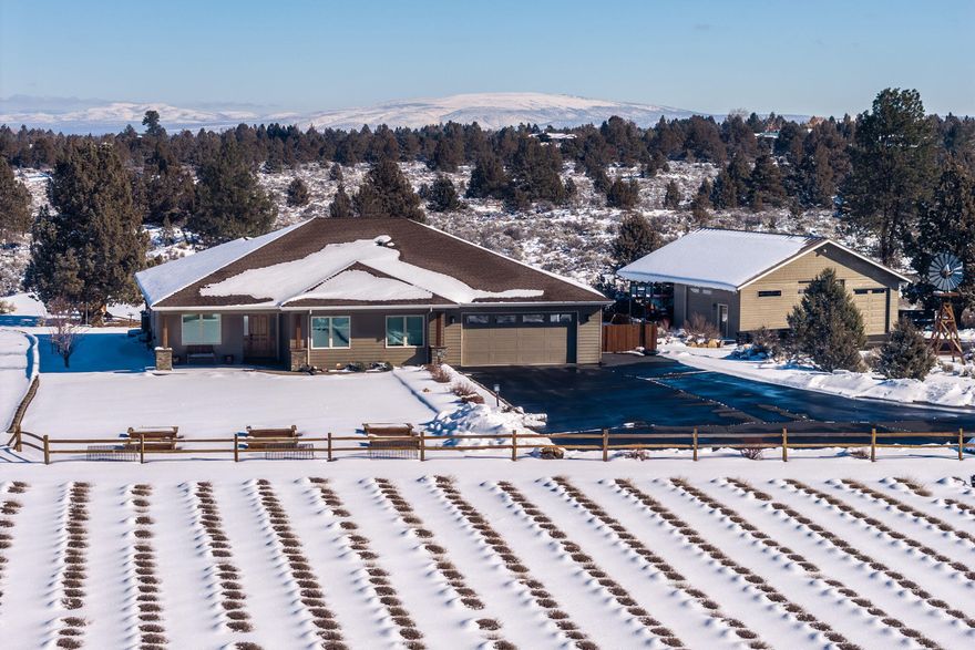 Stunning 9.93-acre property just east of Bend, featuring 7.7 acres of irrigation, a 1445 sq ft shop, and a beautifully maintained single-level home surrounded by lavender fields. Built in 2015, this home showcases quality finishes throughout. The open-concept design is bright and airy with vaulted ceilings, a propane fireplace, and a kitchen with a Travertine-tiled island, granite countertops, stainless steel appliances, custom Hickory cabinetry, and ¾-inch distressed Hickory floors. The dining area includes a large built-in buffet with wine storage. The primary suite offers wool carpet, a walk-in closet, and a luxurious bath with radiant floor heating, a tiled shower, and a soaking tub. There's also a dedicated office and a three-car heated tandem garage. The covered porch, with its cedar ceiling, overlooks the irrigation pond. The shop features three bays, natural light, water and propane connections, insulation, and a mini split for climate control.