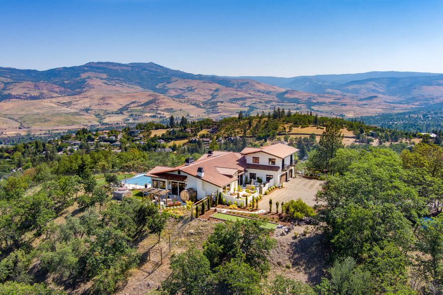 Welcome to Villa Encanto, a truly signature property in Ashland, Oregon providing elegance, comfort, and prestige just over 1 mile from the renowned Oregon Shakespeare Festival. Escape the hustle of town to a world away with unparalleled panoramic views. This Mediterranean masterpiece offers the highest quality fit and finish, all in a warm, modern and comfortable country style. Our Mediterranean climate also polishes this jewel here in wine country. Single-level main living and no-step entry from all doors. Gourmet kitchen offers copper sink, 6-burner Wolf range, and Sub-Zero refrigerator. French doors and windows seamlessly blend the inside with the outside. Master bath is a spa-like experience. Formal dining room showcases a geothermally cooled wine cellar. Heated pool and a strong private well. Outdoor hot tub and sauna, raised bed gardens and 500 lavender plants. There are some really nice homes in Southern Oregon. This is simply one of the nicest.