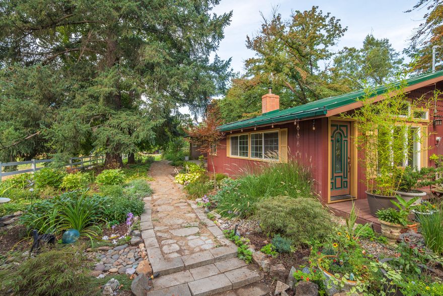 Horse property on 3.61 flat acres with Wards Creek running through the backyard. This 3 bed, 2 bath home offers 2,127 sq ft with a split layout, hardwood floors, granite counters, and an open living area. A spacious bonus room and extra mudroom provide functionality and storage. The large barn/shop includes three stalls ready for your horses plus pasture space. Outside, enjoy a swim spa, fenced dog run, beautiful landscaping, and two additional outbuildings with possible ADU potential. The backyard and covered porch create an inviting space for entertaining while overlooking the creek. Property also includes a metal roof, room for animals, and plenty of parking. Conveniently located in Rogue River, this property combines comfortable living with country charm and endless possibilities for hobby farming or equestrian use.