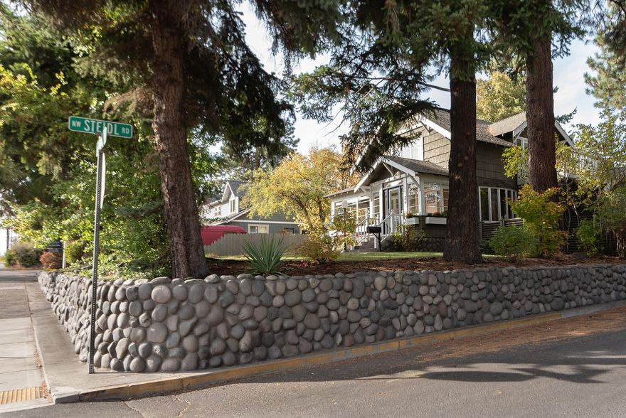 This iconic Bend Craftsman home sits on a elevated large corner RM zoned lot in the coveted River Terrace neighborhood. Just ONE block from Wall Street, Pioneer Park and Deschutes River Trail System. This 4 bedroom, 3 Bath home has new wool carpet, joyful interior paint, new light fixtures & improved landscaping/patios. The kitchen and butler pantry flow elegantly into the dining and living room. The spacious basement is a bonus for extra flex space/storage. Enjoy peaceful river views from your living room, Southside sunroom or from the upstairs primary suite balcony. A fully fenced yard with mature trees provides a haven for all your enjoyment. A few blocks to Bend's premier downtown eateries, boutique shopping and trails. The detached 3 car garage and additional onsite parking provide easy living and RV parking. Don't miss this rare opportunity!