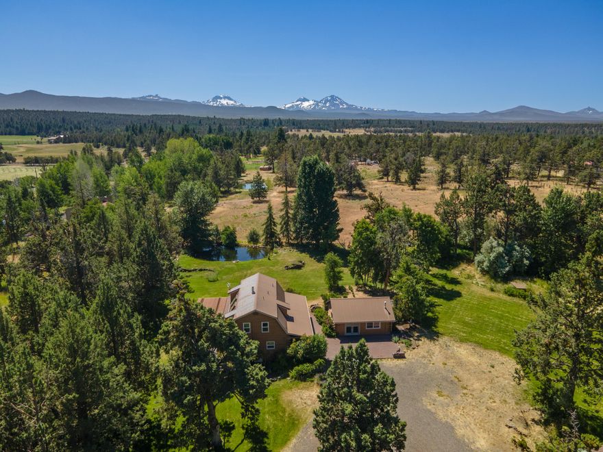 Streaming sunlight mingles with warm natural wood to create an airy and welcoming living space in the heart of this charming, and utterly private, home set on over 5.5 acres in Tumalo. The central gathering room lives large with double height ceilings and skylights that allow natural light to pour in. Out through the French doors enjoy a gracious deck with views of a peaceful tree grove & irrigated pasture beyond. A beautifully renovated kitchen is anchored by a large center island, natural stone countertops, top-of-the-line appliances including a Wolf range, and abundant cabinetry. On the upper level, two large bedrooms enjoy crisp white accent walls with an exceptional view of the large pond & South Sister to the west. An office/third bedroom together with the adjacent studio provide plenty of options for work or play.The 6000 SF covered arena, 5 stall barn, fully fenced perimeter, potting shed & 3.8 acres of irrigation rights, make this an ideal spot for your country living dreams.