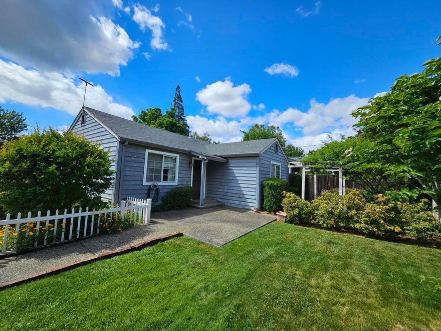 Sweet Country Charmer with a White Picket Fenced! Large 2 bedrooms 1 bath home with vaulted ceilings and laminate in the living and dining areas, tile floors in kitchen, dining area leads to the large utility room and the full bathroom has a ''Safe Step Walk-in- tub'' to relax in, there is also gas heat and FA electric AC. Built in shelves in large bedroom closets, gas range/oven and gas water heater, newer deck off the larger bedroom and kitchen area. The  ducting under the home has been replaced. There's a small shed behind detached 2 car garage 440 St, There's railroad ties for the  retaining wall in side & front yards, with a raised bed with Grape vines. The property in nicely landscaped with a front yard Pergola for relaxing and beauty.