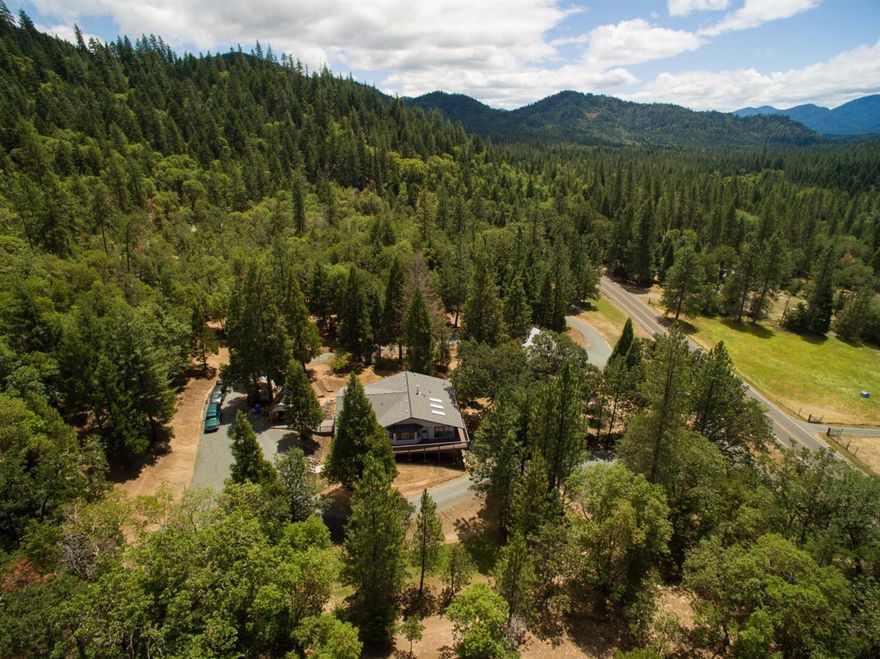 A lovely, pristinely maintained home with end of the road privacy and beautiful mountain views just outside of Rogue River on 11.5 acres; most of which is natural forest setting with seasonal creek. Spacious 3 bedrooms, 3 baths in 3586 sf all with walk-in closets. Huge kitchen with island, pantry, an abundance of cabinets and formal dining. Living room with bay window, newer wood stove and heat pump. Spacious master suite with private bath. Bonus living space/sunroom with skylights to bring in natural light. You will love all the windows. Downstairs you'll find the game room, enormous bedroom, bathroom and additional storage. Circular drive with plenty of parking and very large RV space/pad. Oversized, detached 3 car garage/shop is 20x50 with 220 and more storage. Additional building has workshop and large woodshed. Expansive wood deck is the perfect spot for your outdoor entertaining. Raised garden beds for that vegetable garden you've been wanting. BLM access from part of the proper
