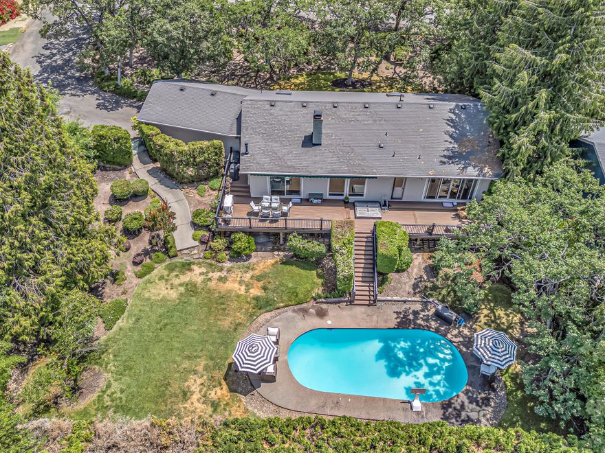 Tucked away in a peaceful East Medford setting with beautiful mountain views, this 1,992 sq. ft. home offers comfort, style, and privacy. Featuring 3 bedrooms and 2 full bathrooms, the light-filled interior showcases newer windows, updated vinyl sliders, and a step-down living room. The modernized kitchen boasts quartz countertops, premium appliances, refreshed cabinetry, and wide-plank flooring, all flowing effortlessly into the main living spaces.  The spacious primary suite highlights a wall of windows overlooking the backyard oasis. Exit outside to enjoy the stunning in-ground pool, wrap-around Trex decking with an automated retractable awning, and a fully landscaped, private yard—ideal for entertaining or relaxing in total tranquility