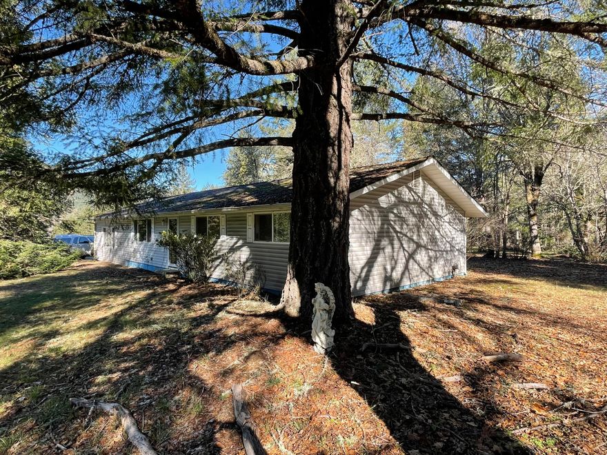 3.6 acres of tranquility in Wolf Creek. This one-level ranch home features 3 bedrooms plus a bonus room, 2 full bathrooms, and a spacious floor plan that is ready for your upgrades. Plenty of room for toys and tools in the 3-car garage and additional lofted barn/workshop. Enjoy the mountain views, mature trees, and year round creek that runs through the property. Just minutes from I-5, Sunny Valley Campground, and local hiking trails. Rare opportunity to build sweat-equity in a stunning and private location!