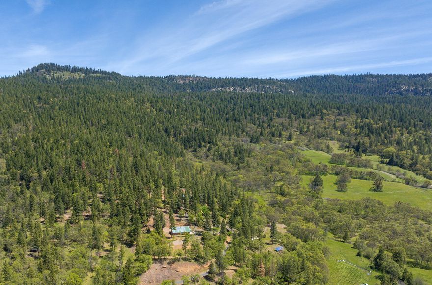 Welcome to your mountain retreat, a sanctuary of privacy & tranquility at the end of a private road. Enjoy breathtaking views of Mount Ashland and the surrounding mountains. At 4,000 feet elevation, this 43-acre property offers fresh mountain air & cooler summers, perfect for escaping city life. Features include irrigated meadows, oak savanna, rolling terrain, & mature evergreen trees. Five ponds, internal roads and trails, & various improvements enhance the property's character and utility. Improvements include a two-bedroom cabin, a 60x40 shop with a man cave, a storage building, a yurt, & a playground. Fully off-grid, the property features solar panels, a generator, a 40-gallon-per-minute well, & an 10,000-gallon water storage system. A 1,872-square-foot home is nearly complete, framed with ICF construction & fully dried in. Embrace a self-sustaining lifestyle with ample space for animals, reliable water, & excellent potential for growing your own food.