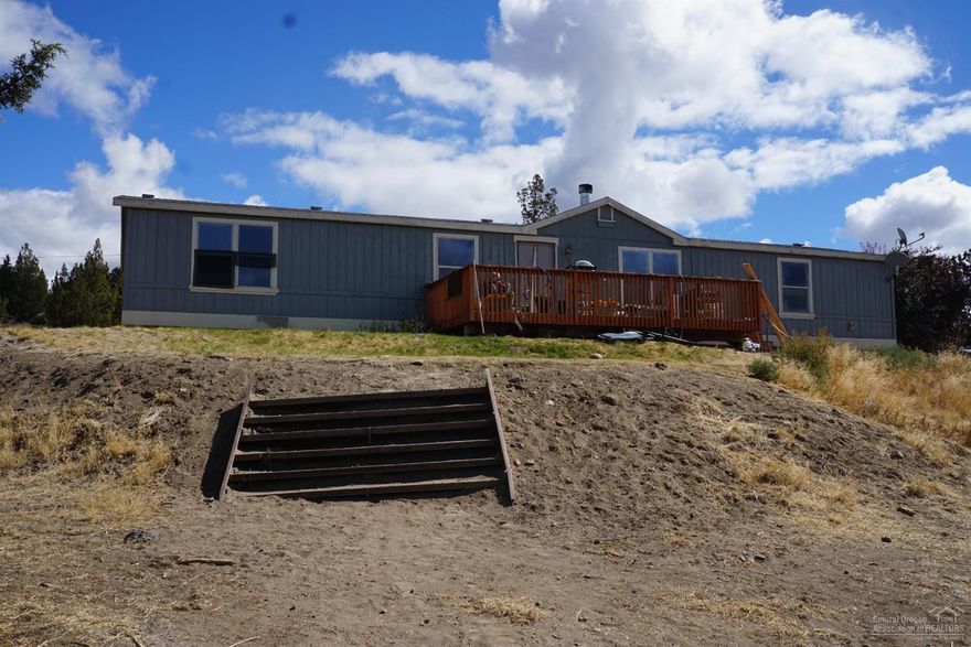 Beautiful mountain views from this 31+ acres with a 1999 manufactured home. Property is fenced and cross fenced and gated for privacy and has potential for dividing, new well pump approx. 2 years ago. Home has a nice layout with a living room and family room with a two sided fireplace dividing the room, living room also has a wood stove, a split floor plan with a good sized master bedroom and bath, open kitchen with an island.