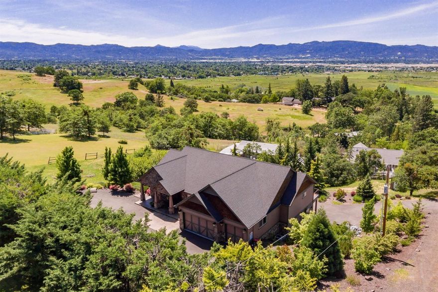 Beautifully crafted custom built home on just over 1 acre with outstanding valley views! Enjoy an East Medford peaceful country atmosphere just minutes to town. Floor plan features two spacious master suites - one on the main level and the other on lower level with private entrance, high vaulted ceilings, large picture windows, three gas fireplaces, formal living room, separate family room, formal and informal dining, office and two laundry rooms plus a bonus room above garage and an additional family room downstairs. Hardwood, stone, and travertine flooring. Kitchen features convection wall oven, built-in microwave, range/oven with 6 burner gas cooktop in island, granite counters and walk-in pantry. Central vac. Security alarm system. Attached 3 car finished garage, RV parking and paved driveway. Nicely landscaped including fenced garden area.