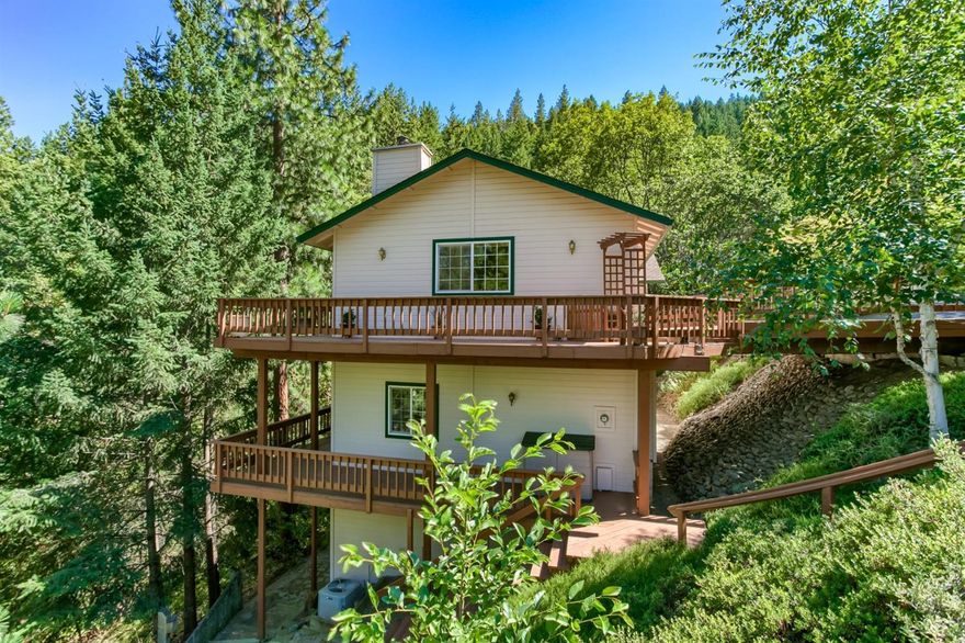 This well-maintained home is nestled in the trees on a large lot surrounded by a beautiful natural woodland. Multiple wrap-around decks with retractable awnings, drip irrigation, and a secluded hot-tub area. Quality features of the home include solid oak flooring, floor-to-ceiling windows, ample built-in storage, anchored book cases, and central vacuum. The kitchen is equipped with convenient laminate flooring, instant hot water, and under-cabinet lighting. The lower level can be accessed from a separate exterior entrance, and is outfitted with certified Jotul wood stove, large recreation room with wet bar, wine cellar, and spacious guest quarters. The grounds have been cleared and landscaped with low-maintenance plantings & a beautiful 17-foot natural rock fountain. Other amenities include a large finished 2-car garage, poured-concrete basement with 18-foot ceilings for additional storage, and copper plumbing. New roof in 2014 and exterior painted in 2016.