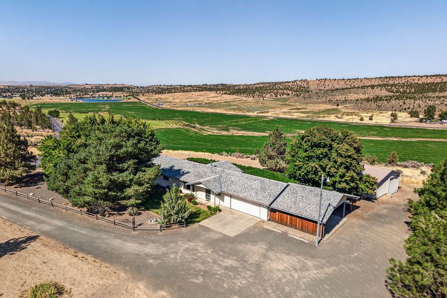Perched on top of the hill with panoramic views overlooking farmland, this 3-bedroom, 2-bathroom home (plus DEN) offers privacy and space. It sits on 3.42 acres. The interior features a large living room with a woodstove, kitchen with scenic views, and an office/den. Enjoy the convenience of a 2-car garage, 2-car carport, and a HUGE 30x30 SHOP with power, plumbing, and heat-- Perfect for projects, storage, or your future hobbies! Towering mature shade trees and landscaping surround the property, with mature grapevines shading the back deck. Plenty of parking for RV, trailers, and other equipment. Zoned RR5, this property allows for horses. A rare opportunity for country living with plenty of room to grow!