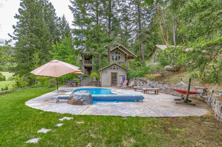 Private, peaceful, perfect. Here's an enchanting 40 acre, whisper quiet woodland estate near Jacksonville. Each 20-acre parcel has a well-stocked bass pond perfect for fly fishing. The 5 bedroom, 4 bath home built in 2002, sits on a gentle knoll overlooking the pastures, ponds, pool & mountain views.  Entertain in a grand-piano sized great room with stone faced fireplace. French doors open to a wrap-around, covered deck. The kitchen & master suite, on opposite sides of the main level, have vaulted ceilings & huge windows to spotlight the views. Custom woodwork throughout. Downstairs a bright 2nd master, family room with fireplace, sauna, 2 bedrooms, covered patio & storage add to this home's spaciousness. Horses are welcome here in their loafing shed.  A sand arena has the proper foundation for building a barn or an arena cover. There are 3 high producing wells. This private property backs up to BLM giving many opportunities for outdoor activities. Truly a place to hang your heart.