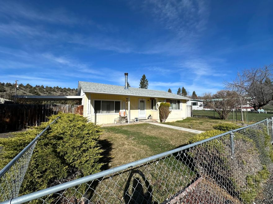 Charming 3-bedroom, 1-bath home offering 1,360 sq. ft. of living space on a 0.22-acre lot. The residence features a modern kitchen adorned with beautiful wooden cabinets and showcases attractive laminate flooring throughout the main living areas. Enjoy the spacious living room and family room, along with a large utility room that provides ample space for a freezer and an extra refrigerator. The expansive fenced yard includes a divider fence that separates the front from the back. Additional storage is available with two metal sheds and a wood shed. Access the alley from the back for easy firewood deliveries or parking for campers and toys. There is plenty of parking in front of the home as well. The heating options consist of a wood stove and an electric furnace. Step out through the sliding glass door to the covered patio for added privacy. This home was built in 1977 and has a tax amount of $1,548.05. MLS# 351324198 Office#399