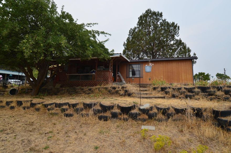 $3,000 Flooring Credit! 1.97 acres with a 1987 Sequoia Double Wide. 24x24 shop with concrete floor, large roll door, lots of shelving, ½ bath, reloading room and additional overhead storage. 36x24 shed with open front so you can park 3 vehicles. Woodshed and additional covered storage. Home has a vaulted living room with open concept. Kitchen appliances are included along with washer and dryer. Primary bedroom has a walk-in closet and tub shower combo. Oil Monitor Stove, forced electric furnace & AC. Covered front deck to take in your view. Apple tree, lilac bushes and juniper trees. Septic and well.