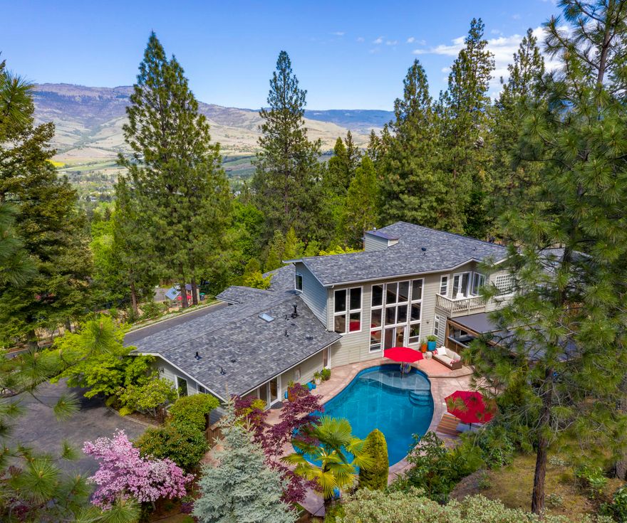 This singular home offers seclusion and serenity within easy reach of downtown. Contemporary design with flowing floorplan is light-filled and surrounded by park-like acreage suited for full-scale entertaining, quiet retreat, work-from-home, cultivator's delight, or all-day relaxation. Expansive valley views from living areas are complemented by the privacy of the pool, spa, outdoor kitchen, fire pit and quiet gardens opening into backyard. The well-appointed chef's kitchen is the heartbeat of open living, dining and family rooms. Laundry, powder bath, storage and exercise/office areas are adjacent. The west wing invites calm with 3 bedrooms/2 baths that converts to guest quarters with separate entrance. Upstairs master presents luxe comfort. Large bedroom with space to lounge, 2 bathrooms and separate glass-walled euro-spa tub. Gated circular drive winds through lower gardens with private vineyard, vegetable garden, fruit trees and greenhouse to arrive at this comforting sanctuary.