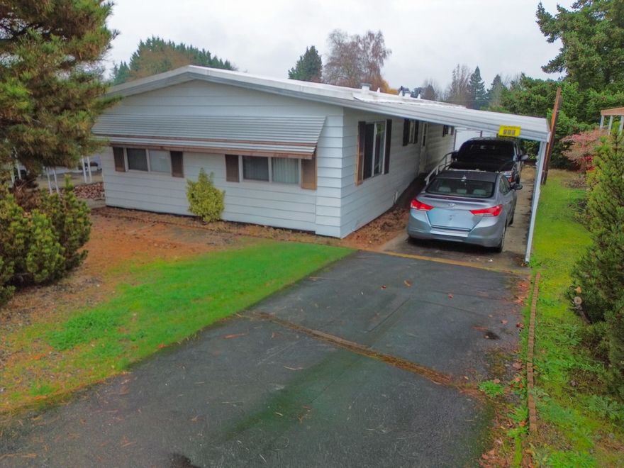 Here is a  well-appointed 2-bed, 2-bath home, featuring an open-concept living/dining area, a functional kitchen with separate cooktop/oven & laundry nearby, a primary suite with a large walk-in shower, a guest bath with a tub/shower combo, good-sized bedrooms, a covered front deck, and practical outdoor amenities like a 2-car carport and storage shed, offering comfort and convenience with defined spaces and utility