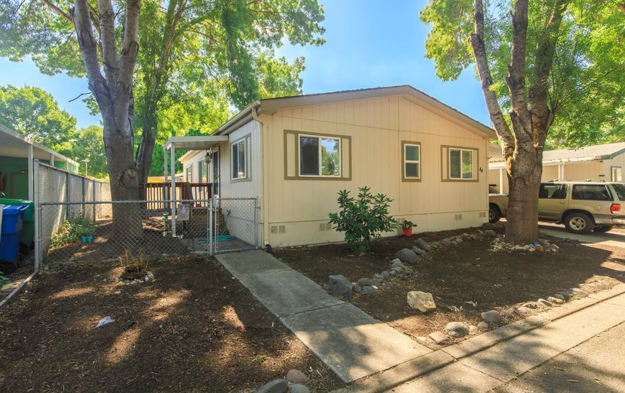 Charming 3-bed, 2-bath home in Butte Crest Manufactured Park! This 1,080 sq ft home features beautiful laminate floors, a stylish updated kitchen with a corner pantry, and a desirable split floor plan for added privacy. The fully fenced backyard offers a tranquil corner water feature—perfect for relaxing outdoors. Enjoy springtime blooms with tulips lining the walkways and front yard. Extra-long storage shed under the carport provides ample space for tools and more. Move-in ready and located in a welcoming, well-kept community!