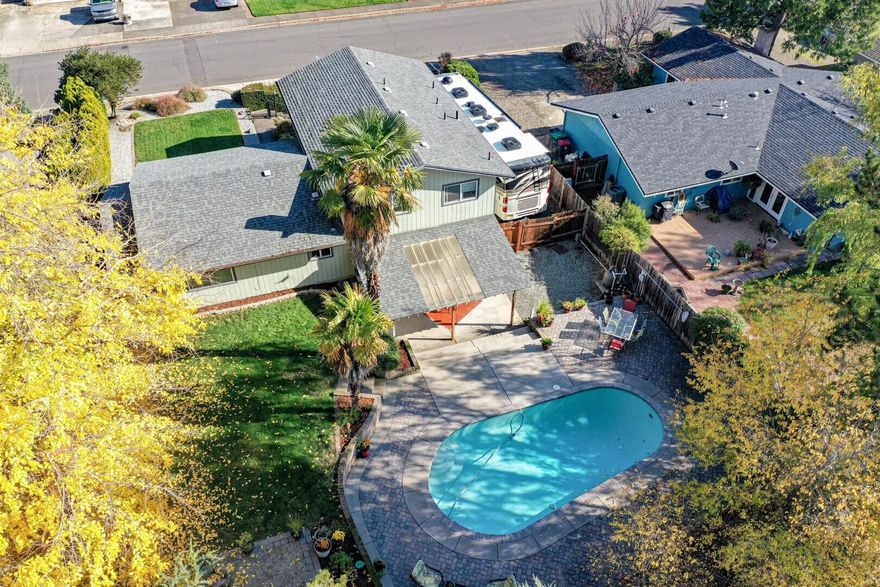 Tri-level residence set in a popular, close-in, mature East Medford neighborhood. The large private lot offers a spacious front lawn/play area and a custom-built oval swimming pool & lawn area & covered patio in the back yard. Enter the main living area with the kitchen, dining room & living room with RoxyAnn mountain views. 3 bedrooms & 2 baths are up a few steps and the family living center with stone heatilator fireplace & half bath is just a few steps down from the main living area. A large laundry room with sink and storage is also on the lower level. The  2-car garage is attached plus there is excellent off-street driveway parking and space for an RV up to about 40 feet with 50 amp power and water supply. Covered storage on the side yard. Located close to the new Medford Cedar Links Park with grass areas, walking paths, play structure, dog park, basketball and pickleball courts.