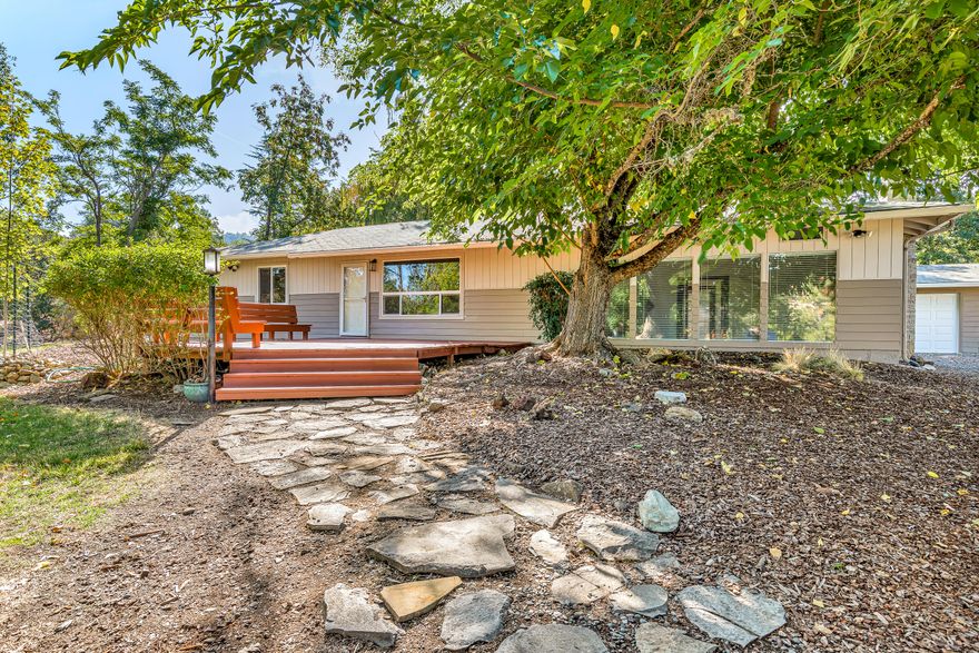 Nestled in the peaceful hills just south of Medford, this 2.18-acre flat property is a secluded paradise.  Built in 1963, the home has had many updates & has an open, flowing floorplan including 3 bedrooms & an office/bonus room with a Murphy bed. Original refinished hardwood floors add warmth & charm, while oversized windows allow you to view your beautiful surroundings.  You'll love the sunken living room, complete with slate tile floor & cozy woodstove. The kitchen features recently painted cabinets, a new stove & microwave, & concrete counters.  Other recent updates include a new HVAC system in 2022 & new water heater in 2020.  Outside, you'll find a seasonal creek, a large deck to enjoy the peaceful surroundings, a detached 2-car garage with space for a workshop, as well as a nearly 1,300 sq ft fenced garden to grow all your veggies. You can enjoy your own mini-orchard with a few mature peach, apple & cherry trees!  This property is a must-see! Call today for a showing!