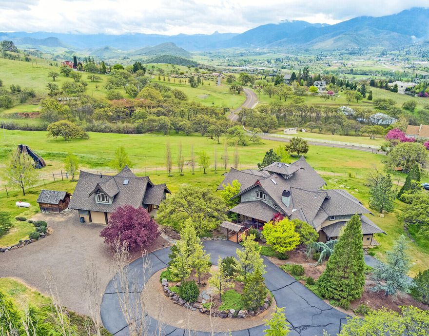 Pastoral, peaceful, private. Set on 6+ acres, this custom-built, Zen-inspired home has unparalleled mountain & valley views. A gated driveway leads you up a gentle hill. As you cross the foot bridge to the main home, a feeling of serenity comes over you. Stunning views of Mt Ashland & the Siskiyous greet you as you enter. Slate floors, tile work, open floor plan & exquisite wood detailing exhibit the construction craftsmanship. The spacious master features a gorgeous tiled, walk-in shower, walk-in closet, toilet room & access to the deck. The office features a staircase to a balcony meditation/exercise room. The lower level has a 2-bedroom apartment with fireplace, full kitchen, laundry, covered patio, exterior access & garage. A detached, oversized 2-car garage with laundry hookups, has an upper-level studio with fireplace to keep your guests cozy. This window wonderland takes advantage of the miles-wide views from every room, as does the deck. It is truly a place to hang your heart.