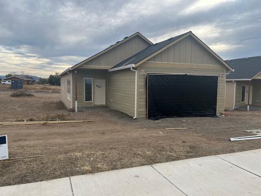 Stunning new construction offers an open floor plan w/ 9' ceilings, mini split A/C unit and beautiful views of the Cascade Mountains. This kitchen showcases quartz counters, stainless steel appliances and durable LVP flooring throughout the main living areas. The bedrooms are carpeted for comfort and the spacious primary ensuite includes a walk-in closet and ceiling fan. A fully fenced yard adds privacy and functionality. Additional highlights include a double car garage at the front and convenient alley access - perfect for trailers, RV's or extra parking. ENJOY THE FREEDOM WITH NO HOA'S OR CC&R'S...NO RESTRICTIVE RULES OR ADDITIONAL COSTS.