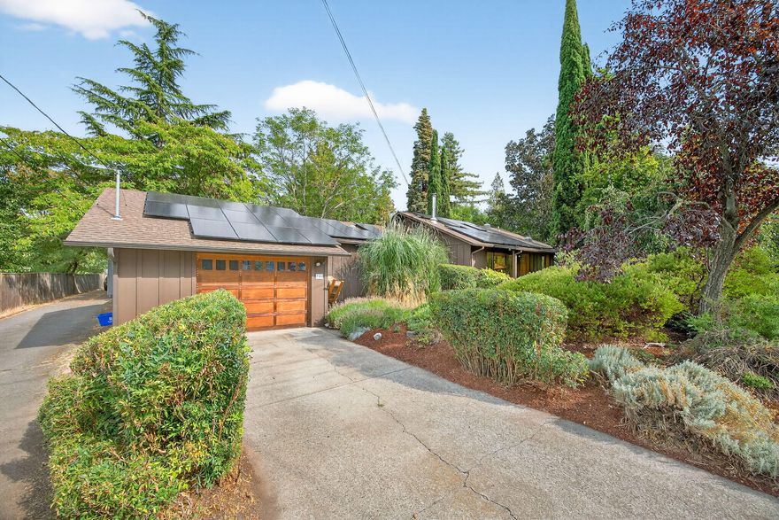 Single-level home with a warm and vibrant feel. The open floor plan with vaulted ceilings, skylights, and a cozy wood stove creates a welcoming atmosphere. A spacious kitchen with custom cabinetry, butcher block counters, and quality appliances flows easily into the living and dining areas, perfect for gathering. The private primary suite offers a walk-in closet and bath, while two additional
bedrooms provide flexibility. An air-conditioned bonus room off the garage adds even more versatile living space—ideal for a home office or studio. Outdoors, mature landscaping, fruit trees, and abundant gardens thrive in enriched soils, creating a true gardener's oasis. Solar panels keep energy costs low, and the setting feels private and peaceful while still close to town.