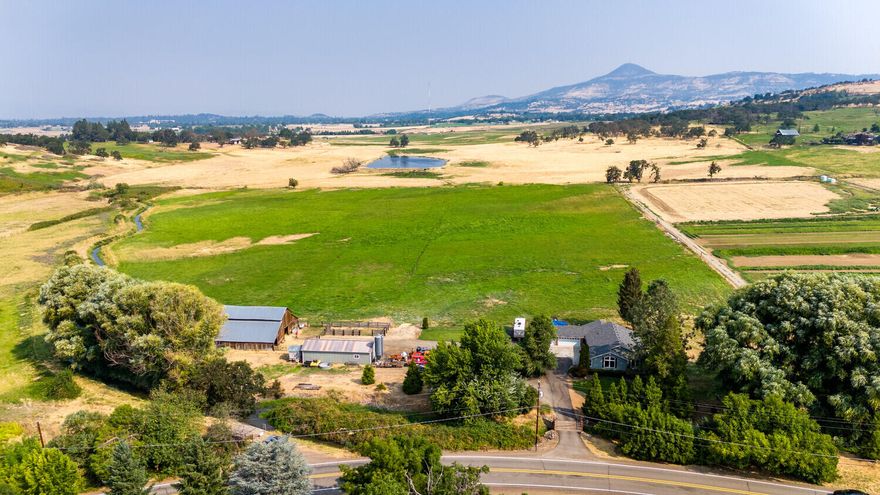 Panoramic vistas of the Rogue Valley surround this remarkable property. Discover tranquility on this 20.27-acre haven, part of the Phoenix Urban Reserve but tucked away, the perfect blend of convenience and rural charm, w/future potential. The original home was taken down to a small foundation section then all new construction in 1999. This 1923 SF single level home, 3 car garage & RV parking is beautifully finished, built with quality throughout. Enjoy the gracious primary bedroom with private deck & relaxing views of elegant willow trees & mature landscaping. Beautiful light pours in through the many windows, large open kitchen, dining & living space complimented by new luxury vinyl plank flooring. Covered breezeway & patio provide shade for enjoying quiet meals outside.  TID flood irrigation & plenty of space for self-sustained living, organic gardening, horses, vineyard, livestock, or THC, hemp.  A separate 804 SF garage/shop and large barn are ready to house equipment & animals.