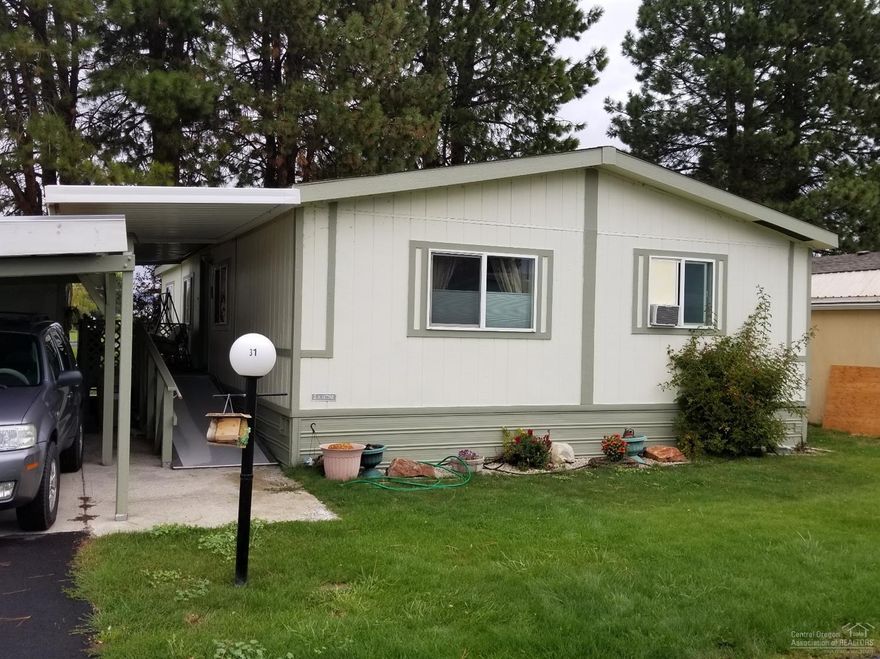 Nicely updated manufactured home in desired park. This 3 bedroom, 2 bath home features an open floor plan with master bedroom on opposite end of the 2 guest rooms. A nice, cozy wood stove sits in an area that could be used as an additional sitting area/office area adjacent to the living room. Home sits on a corner space with a well cared for lawn. Located just minutes from town, yet definitely has a quiet country feel. Lots of outside storage too, with covered carport and newly built ramp to front door. This won't last long. Come and take a look!